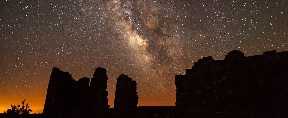 The Milky Way arcs above a silhouetted rock structure The Milky Way arcs above a silhouetted rock structure
