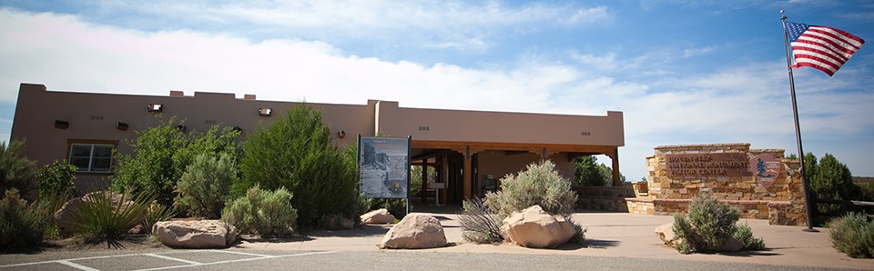 a low, tan building with a US flag flying on a pole outside