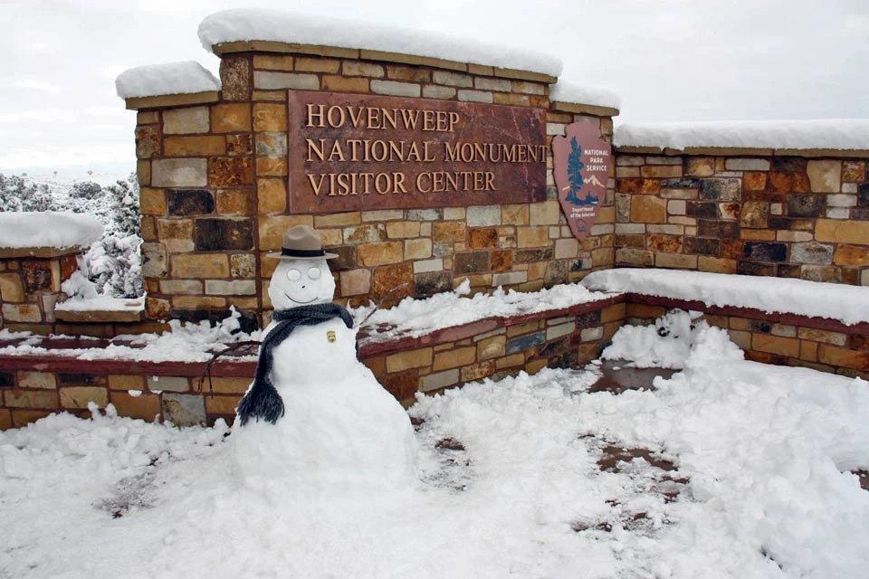 snowman in front of visitor center snowman decorated as a park ranger in front of the visitor center sign