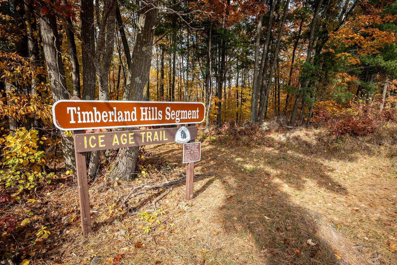 Photograph of autumn forest with sign saying Timberland Hills Segment Ice Age Trail