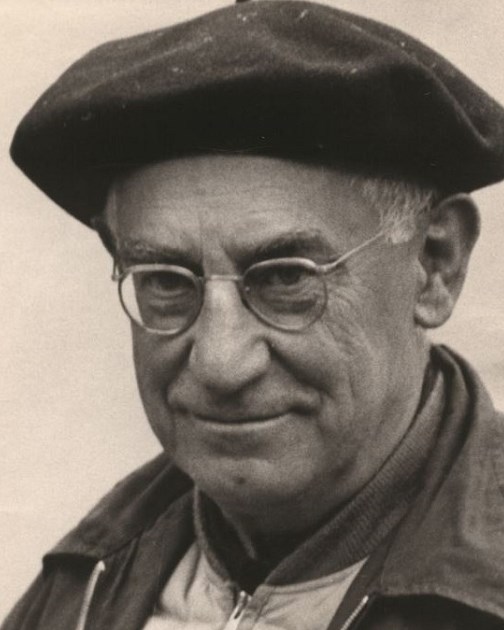 Photograph of man with wire glasses and a black beret.