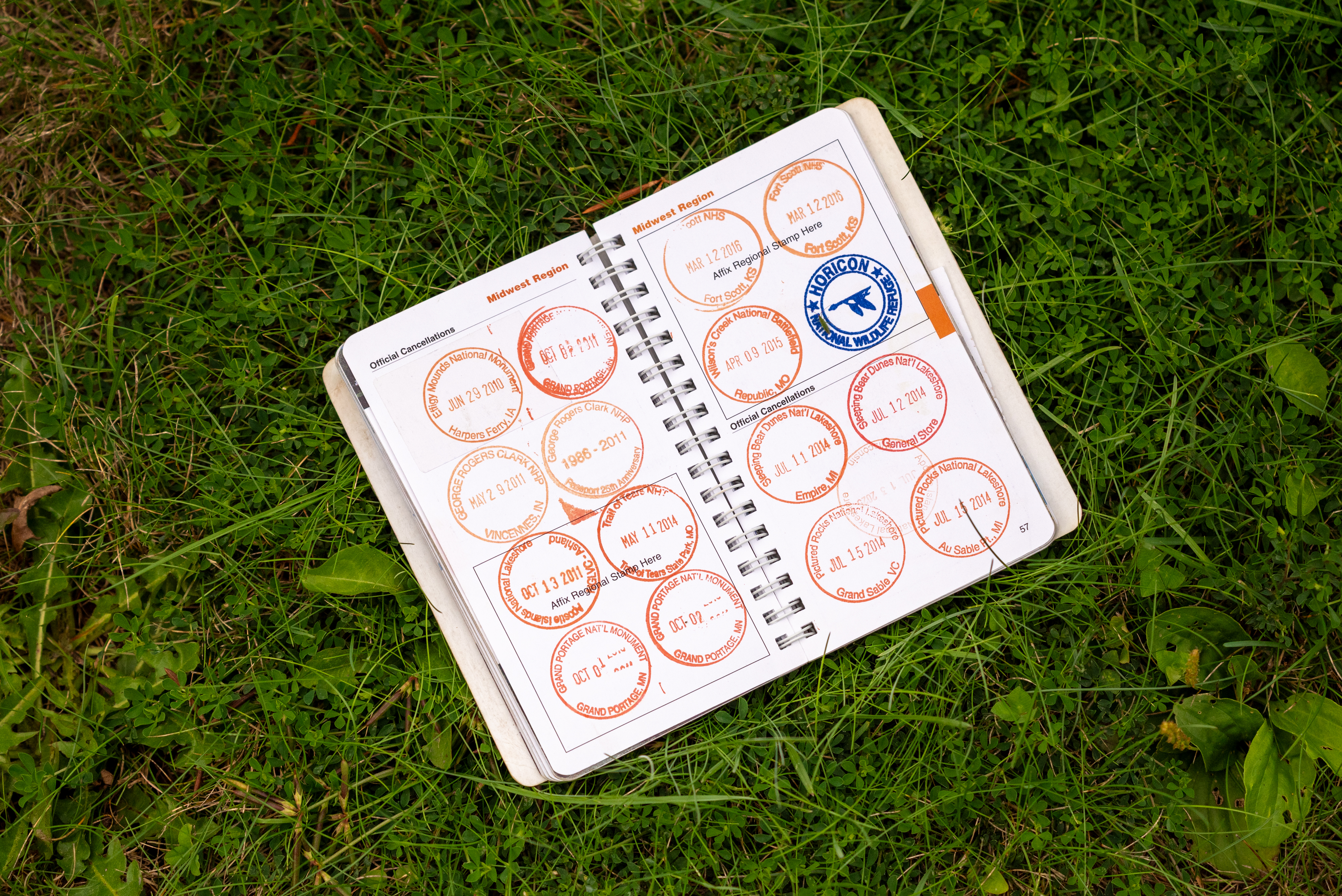 Photograph of small spiral-bound notebook with many circular stamps.