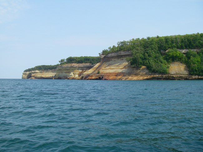 Red, tan, and gray rock cliffs along the lake