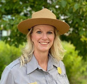 A woman with long blond hair wears a ranger hat and uniform.