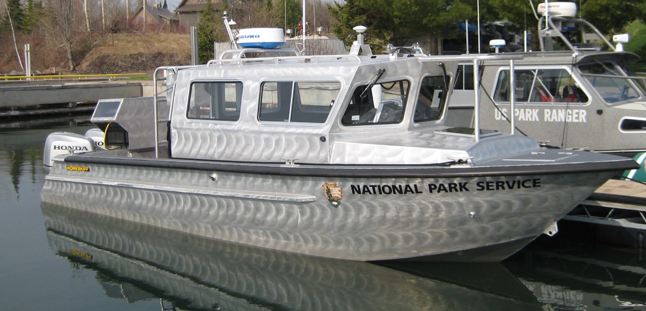 A silver boat tied up at a dock