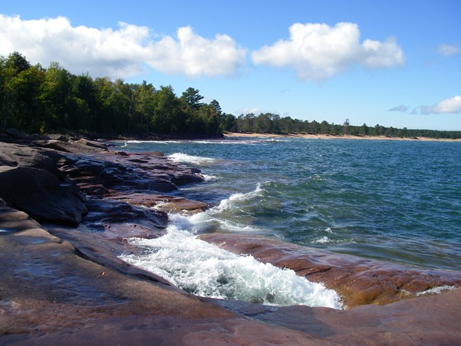 Sandstone shore, blue lake, and distant beach