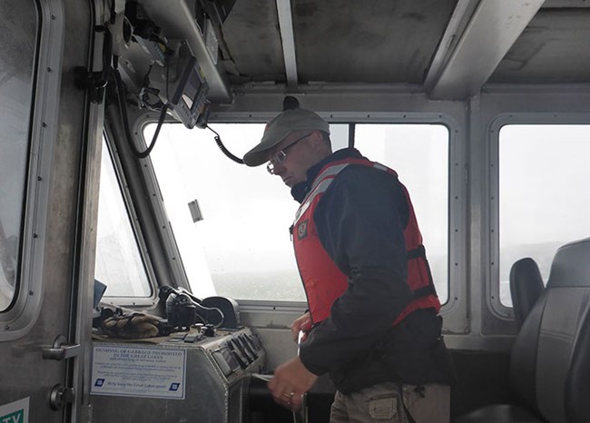 a man standing at the helm of a boat is looking at instruments