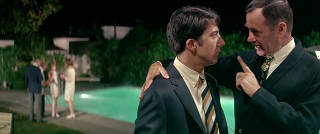 TheGraduate_IMDB A man with his right hand on a young man's shoulder and his left hand with the index finger raised as he speaks
