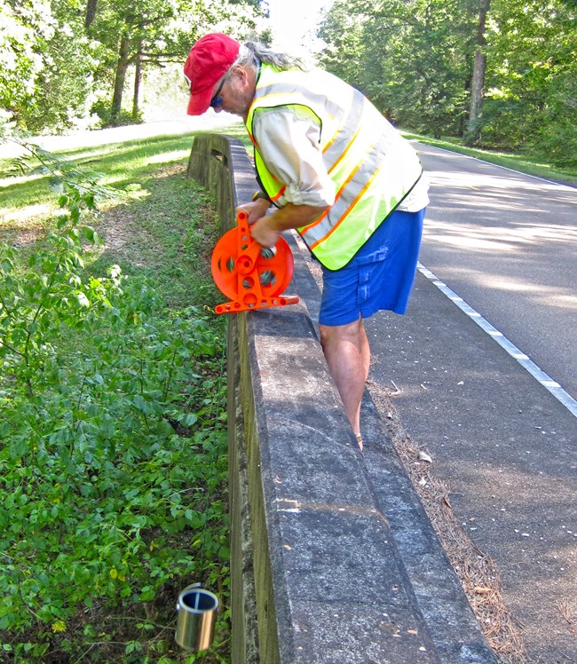 Water being sampled from a stream beneath a bridge on the Natchez Trace by lowering a bucket from the bridge