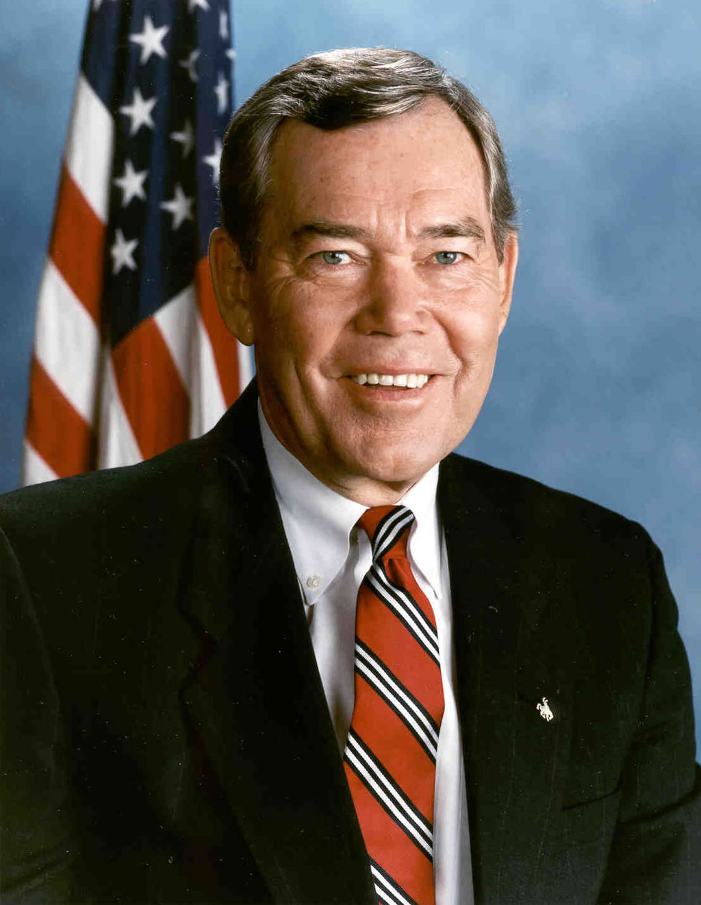 Smiling White man in black suit and red tie, American flag behind. Smiling White man in black suit and red tie, American flag behind.