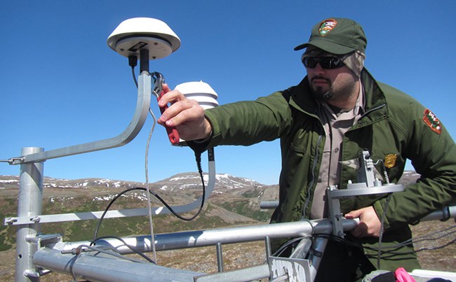 Park employee in a remote area fixing a weather station