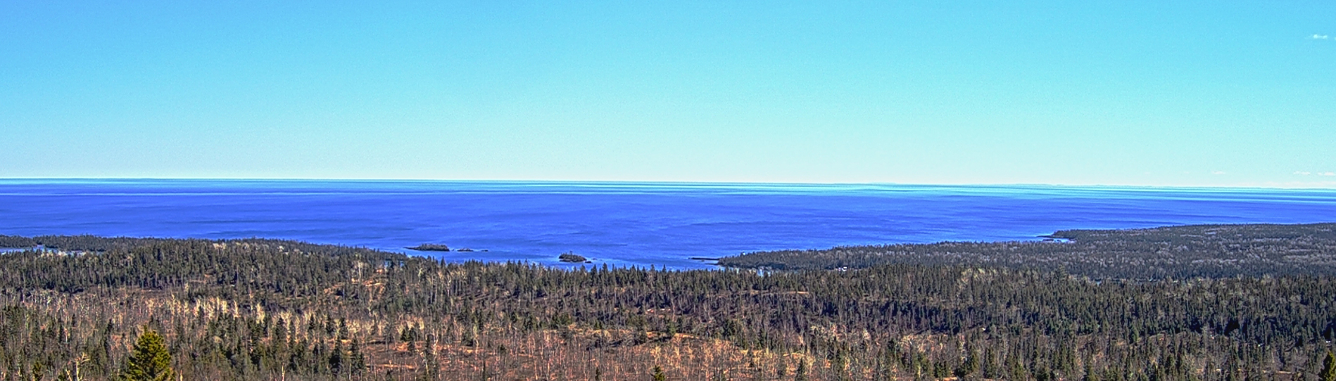 An expanse of blue water and a tree-covered shoreline.