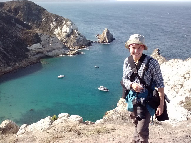 Jessica on a bluff overlooking a small bay with turquoise water.