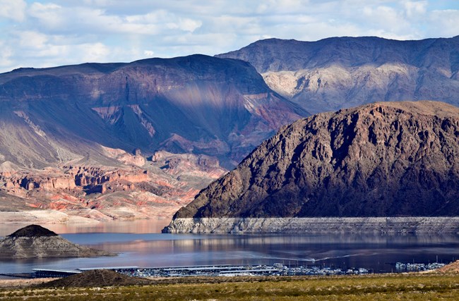 hills shaded by clouds surround a basin of water