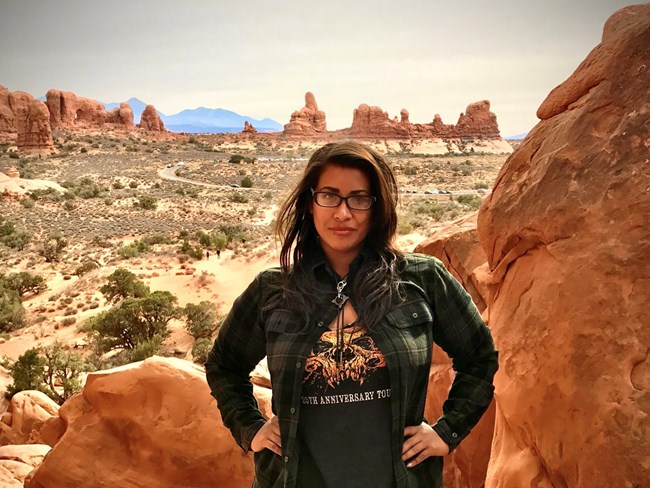 Flor Calderon, Biological Technician Woman standing with hands on hips amidst red sandstone rock formation