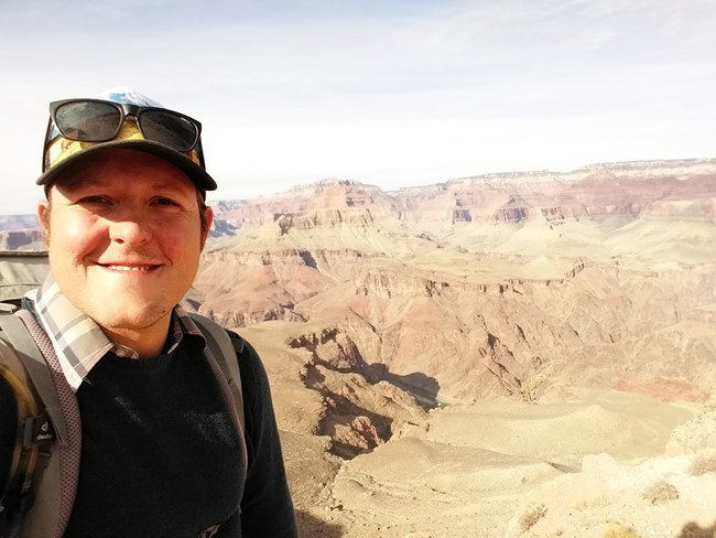 Joseph Ladd, Biological Science Technician, wearing backpack and with desert landscape in background