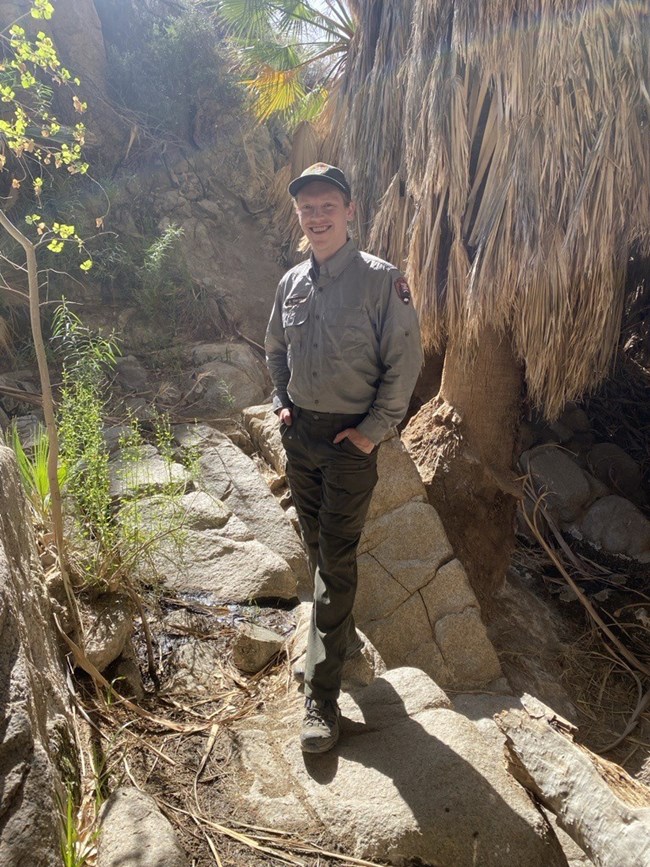 Kyle Smith, Vegetation Technician Man in park service uniform standing next to a desert palm.