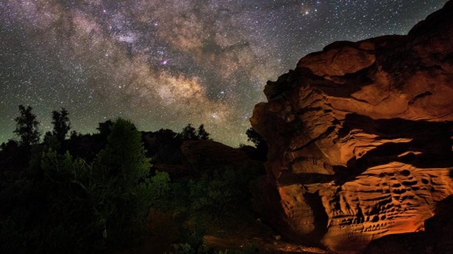 The Milky Way and night sky arching above a dark landscape