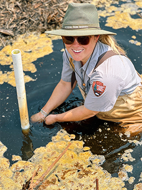 Katie Button Katie installs a water logger in a marsh.