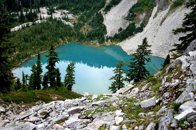 Emerald green lake surrounded by steep talus and evergreens