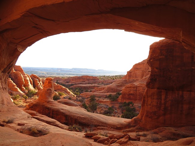 Red rock landscape framed by natural arch