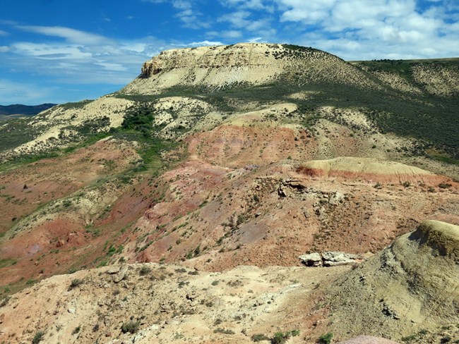 The colorful slopes of Fossil Butte tell a story of ancient lakes and rivers—where red, pink, and yellow clays of the Wasatch Formation meet the pale limestone of the Green River Formation’s Fossil Butte Member. Layered ridge with white Fossil Butte Member above red Wasatch Formation slopes