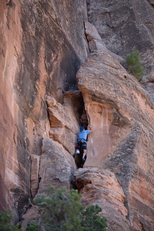 Rock climber on a sandstone formation Rock climber ascending a vertical sandstone wall
