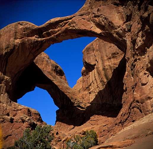 Natural sandstone arches under blue sky at Arches National Park.