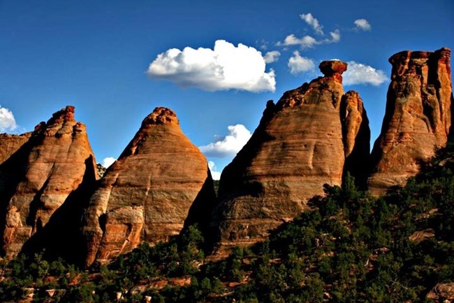 Coke Ovens formations in Monument Canyon showcase layered sediment sculpted by erosion. Coke Ovens rock formations in Colorado National Monument under blue sky