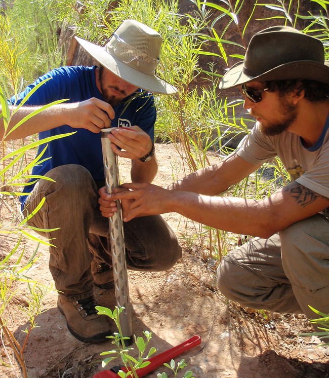 Two men install a groundwater well