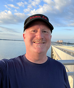 Eliot Rendleman, NPS Writer-Editor, on a bridge over Biloxi Bay Selfie of Eliot Rendleman, NPS Writer-Editor, with Biloxi, MS, and Biloxi Bay in the background.