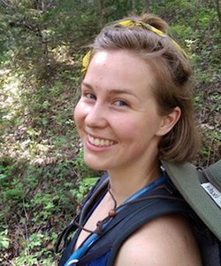 Woman wearing backpack smiles at camera