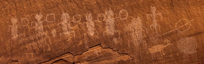 rock art NPS Jacob W. Frank Petroglyphs carved into red sandstone wall at Natural Bridges National Monument.