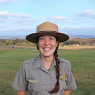 headshot of smiling woman in park service ranger hat