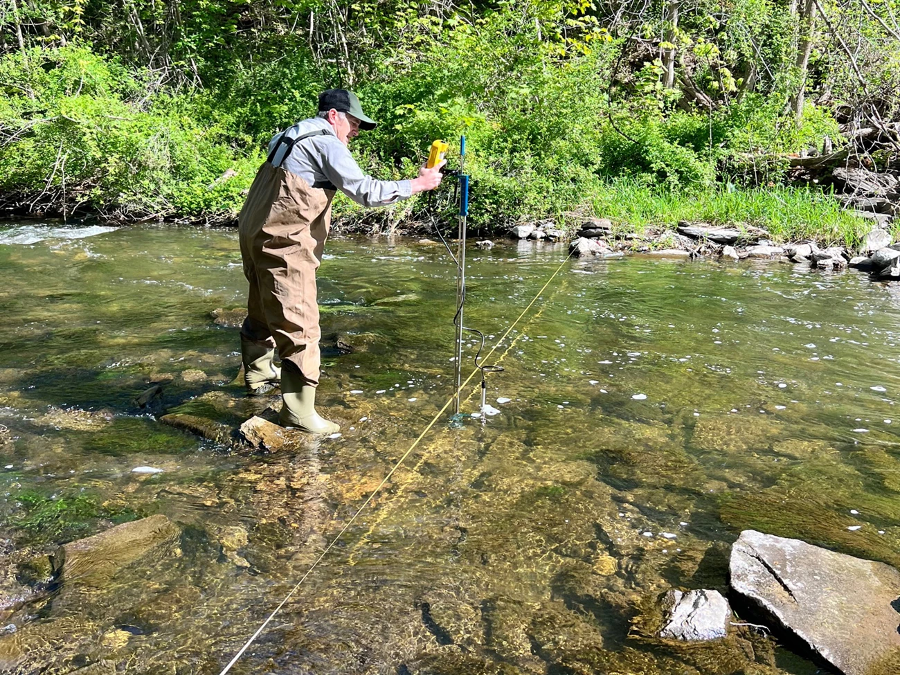 ROVA WQ monitoring An NPS tech stands in a shallow stream with wq monitoring equipment