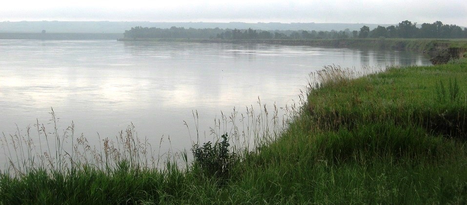 wide river on a cloudy day with grassy bank in the forground