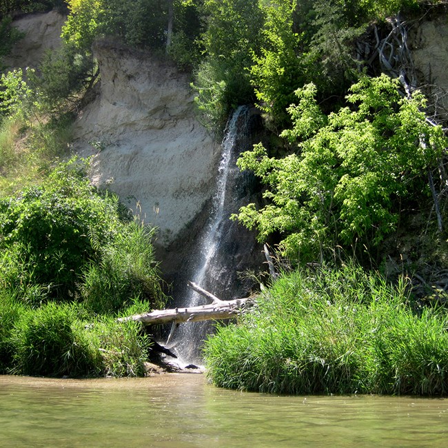 Waterfall along the Niobrara River waterfall pouring into a river with green vegetation around it