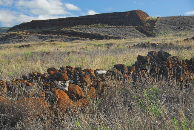Pu‘ukoholā Heiau landscape The remains of a rock wall in the foreground with the temple in the distance