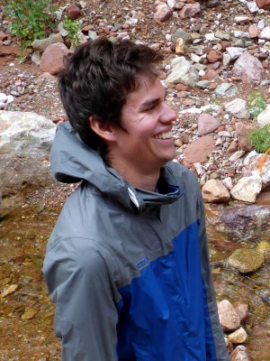 Man with grey and blue jacket smiling broadly.