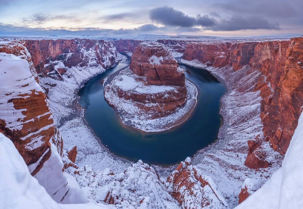 Horseshoe Bend at Glen Canyon National Recreation Area Looking down at a large bend in a river, with canyon walls covered in snow.