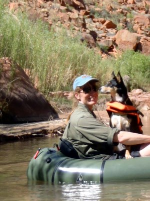 Woman wearing a cap, with a dog, in a raft.