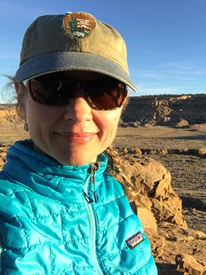 Woman with hat and sunglasses wearing blue jacket