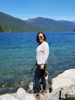 Person in sweater standing by blue lake