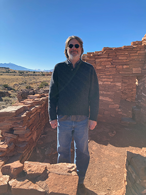 Bearded man with glasses standing near an ancestral puebloan ruin