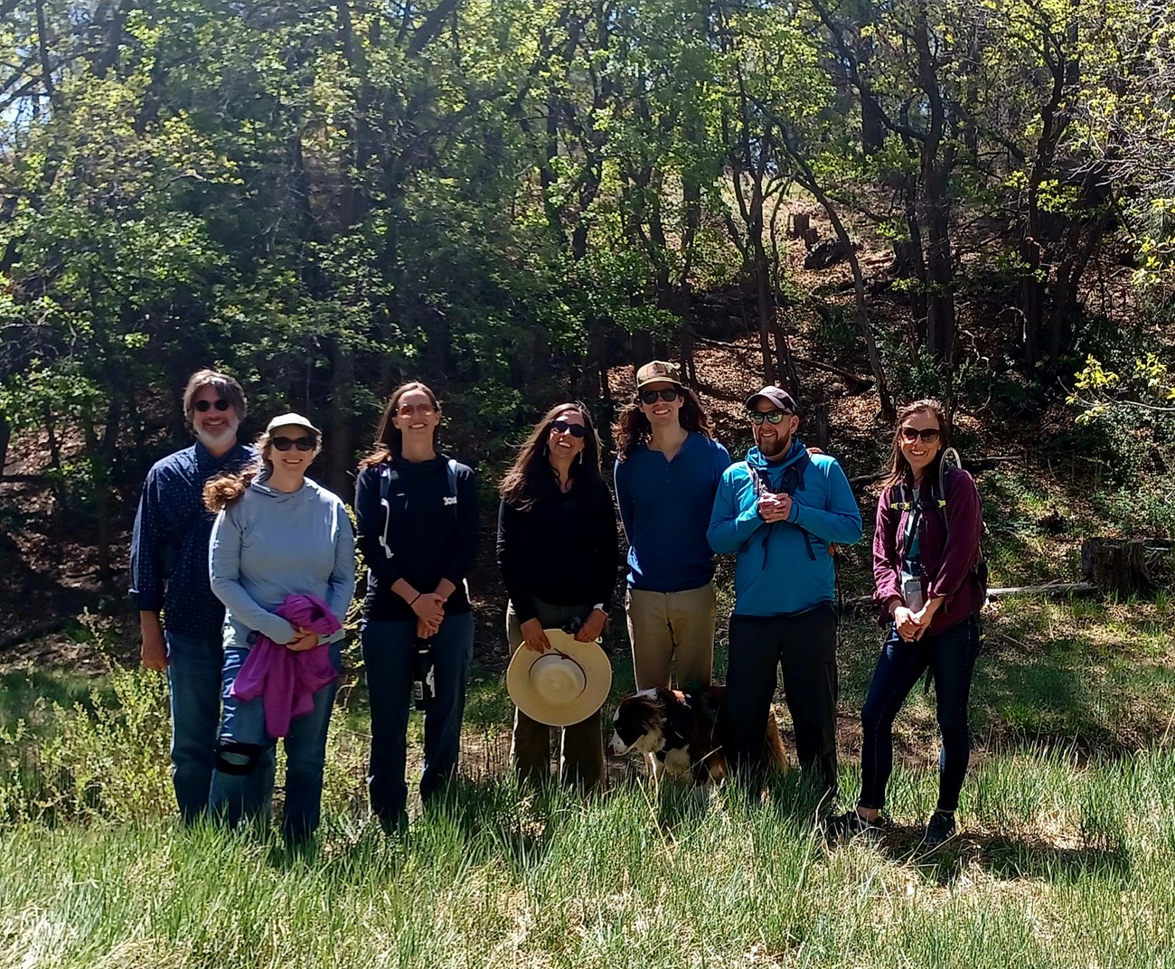 SCPN staff and Meg White at Picture Canyon. Seven smiling people and one dog standing side by side in an oak forest.