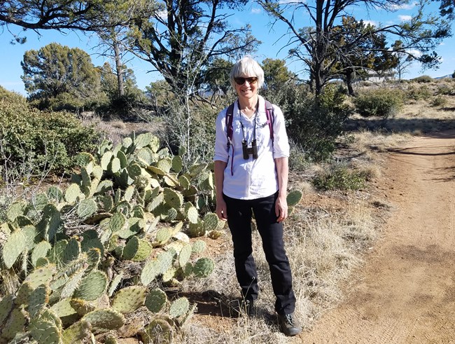 Linda Mutch Woman stands on trail near cacti