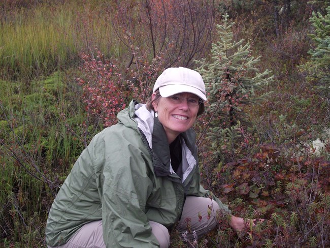 Sylvia Haultain, Program Manager Woman poses smiling in front of tundra shrubs and small tree.