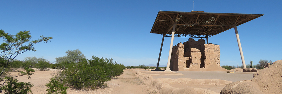 Archeological ruin with roof over it, green shrubs nearby