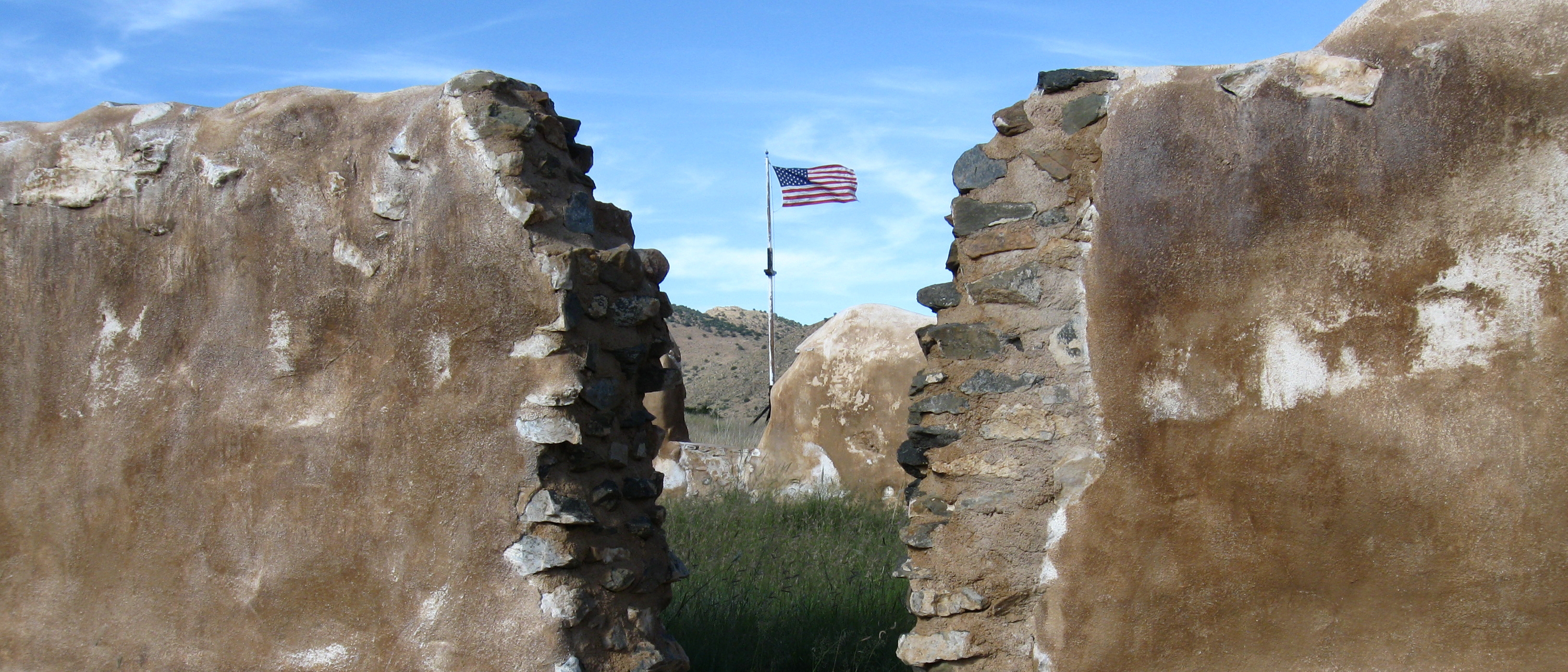 American flag viewed through the remains of an adobe doorway.