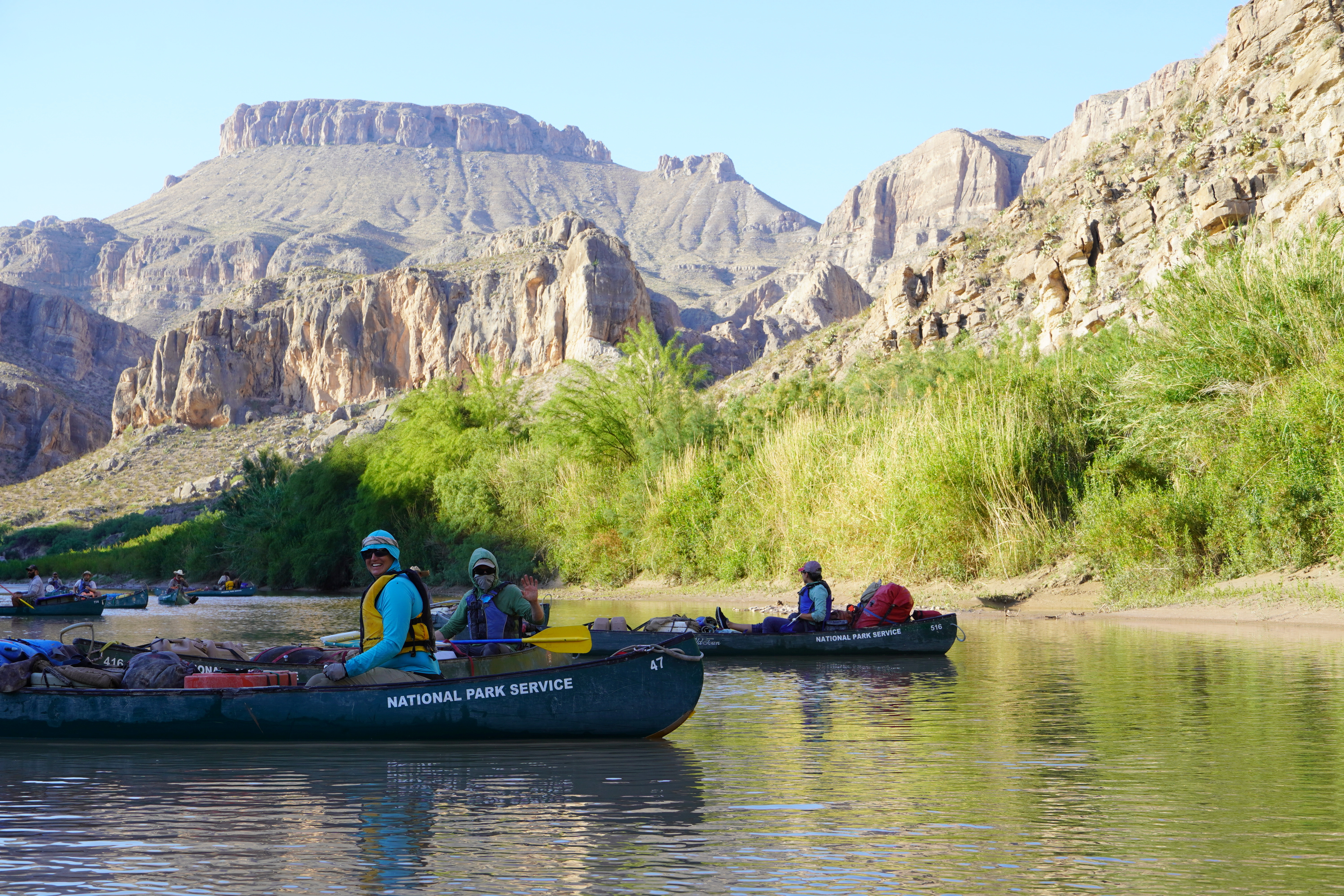 People sit in rafts marked National Park Service. People sit in rafts marked National Park Service.